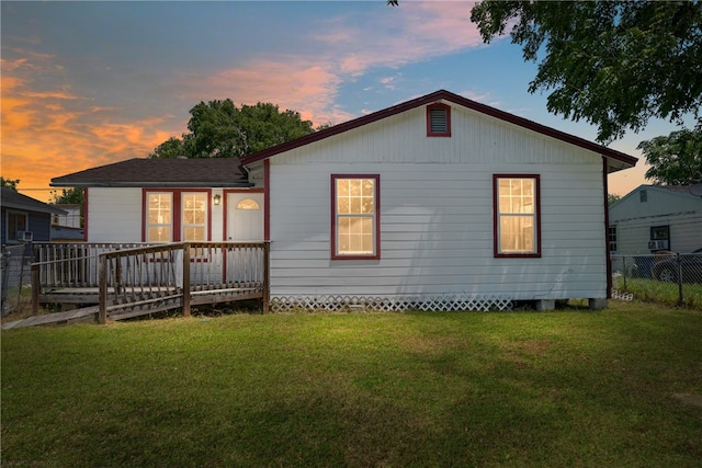 back house at dusk with a yard and a deck