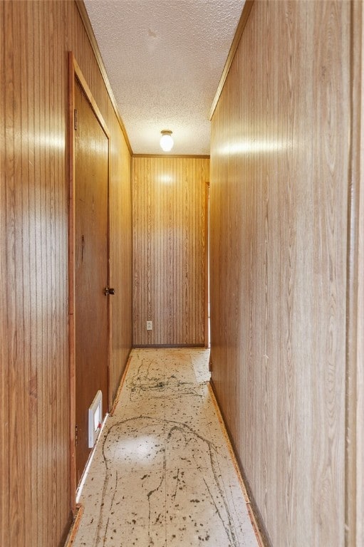 hall with wooden walls and a textured ceiling
