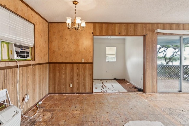 unfurnished dining area with ornamental molding, wooden walls, cooling unit, and a chandelier