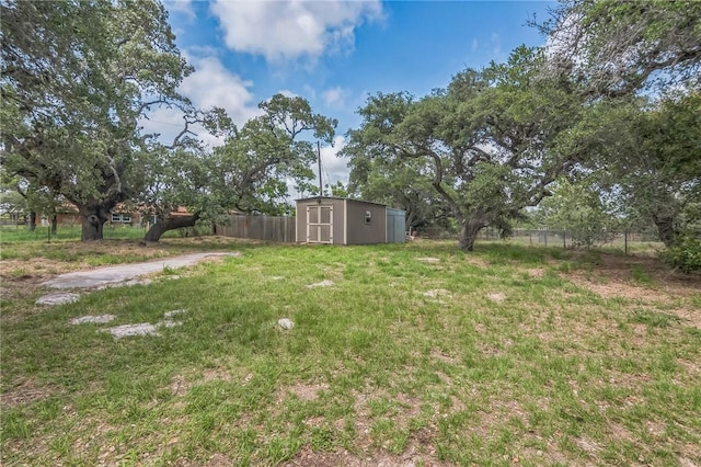 view of yard with fence, a storage unit, and an outbuilding