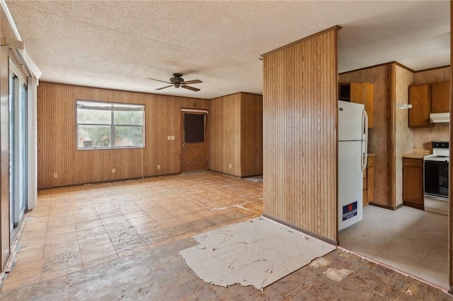 interior space featuring freestanding refrigerator, a textured ceiling, under cabinet range hood, brown cabinets, and a ceiling fan