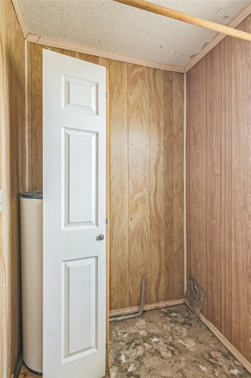 spare room with wooden walls, gas water heater, and a textured ceiling