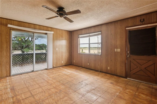 unfurnished room featuring wood walls and a healthy amount of sunlight