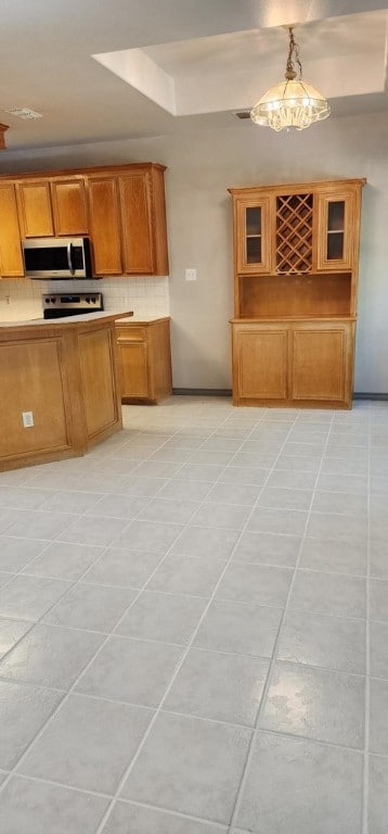 kitchen featuring backsplash, hanging light fixtures, light tile patterned floors, and a notable chandelier