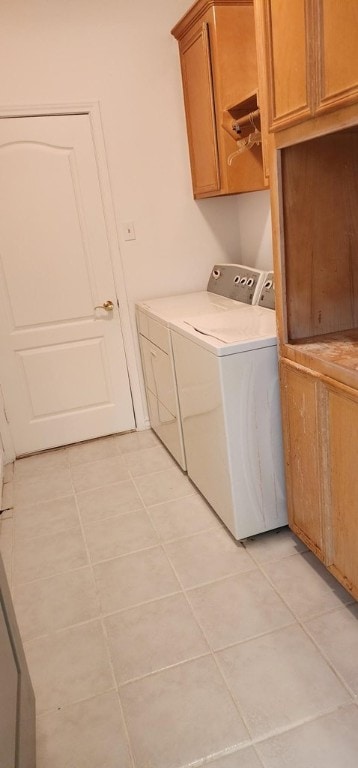 laundry area featuring washer and clothes dryer, cabinets, and light tile patterned floors