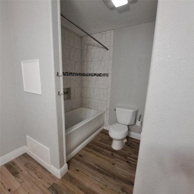 bathroom featuring toilet, wood-type flooring, and tiled shower / bath