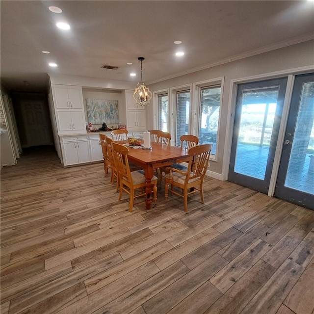 dining room with an inviting chandelier, light hardwood / wood-style flooring, and crown molding