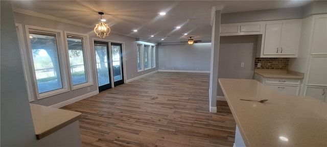 kitchen featuring backsplash, hardwood / wood-style floors, pendant lighting, white cabinets, and ornamental molding