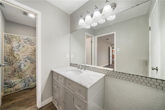 full bath featuring a shower with shower curtain, baseboards, wood finished floors, and vanity