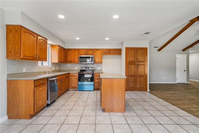 kitchen with appliances with stainless steel finishes, light countertops, brown cabinets, and tasteful backsplash