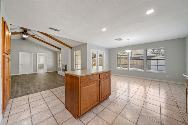 kitchen featuring a center island, light tile patterned floors, lofted ceiling, light countertops, and open floor plan