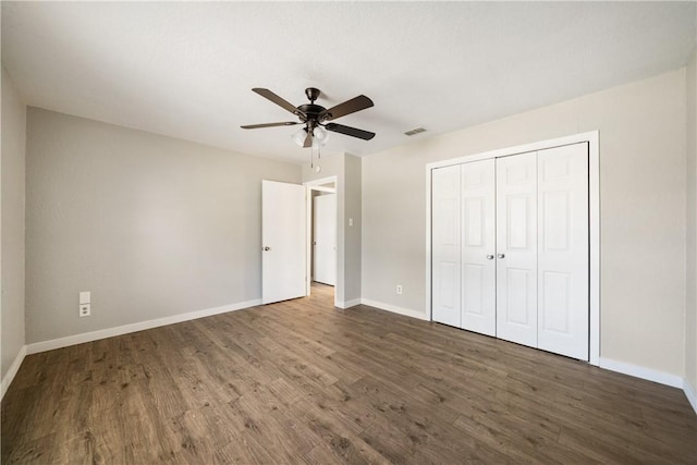 unfurnished bedroom with wood finished floors, a ceiling fan, visible vents, baseboards, and a closet