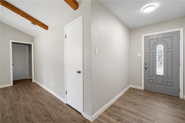 foyer featuring vaulted ceiling with beams, visible vents, baseboards, and wood finished floors