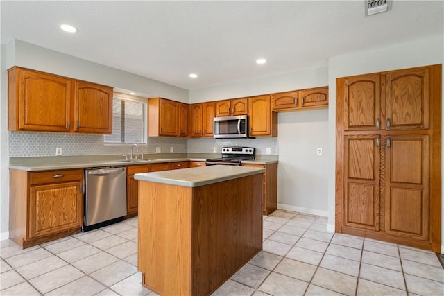 kitchen with visible vents, appliances with stainless steel finishes, brown cabinets, a center island, and a sink