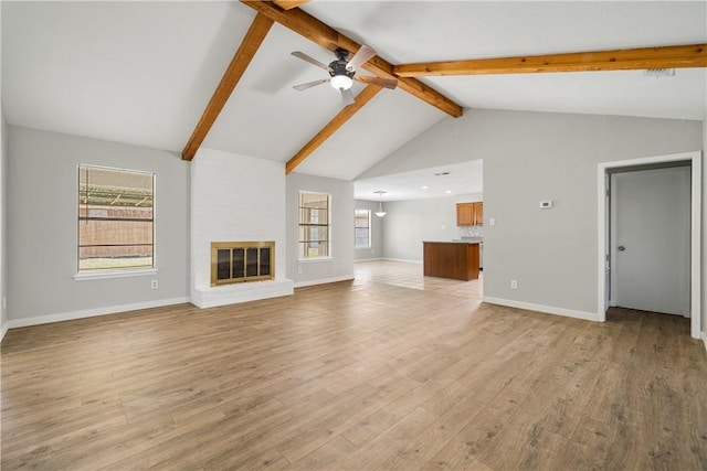 unfurnished living room featuring light wood-type flooring, a brick fireplace, a ceiling fan, and beamed ceiling