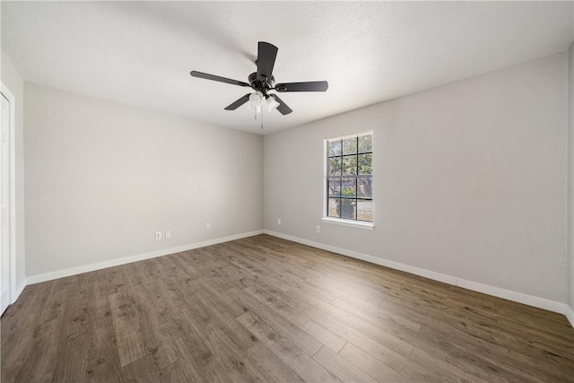 empty room with ceiling fan, wood finished floors, and baseboards