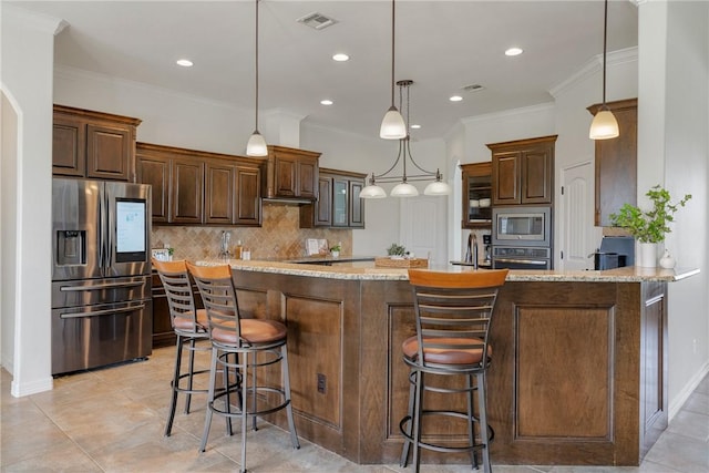 kitchen featuring a kitchen bar, appliances with stainless steel finishes, kitchen peninsula, light stone counters, and hanging light fixtures