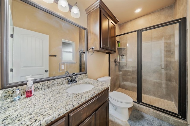 bathroom featuring a shower with door, vanity, and toilet