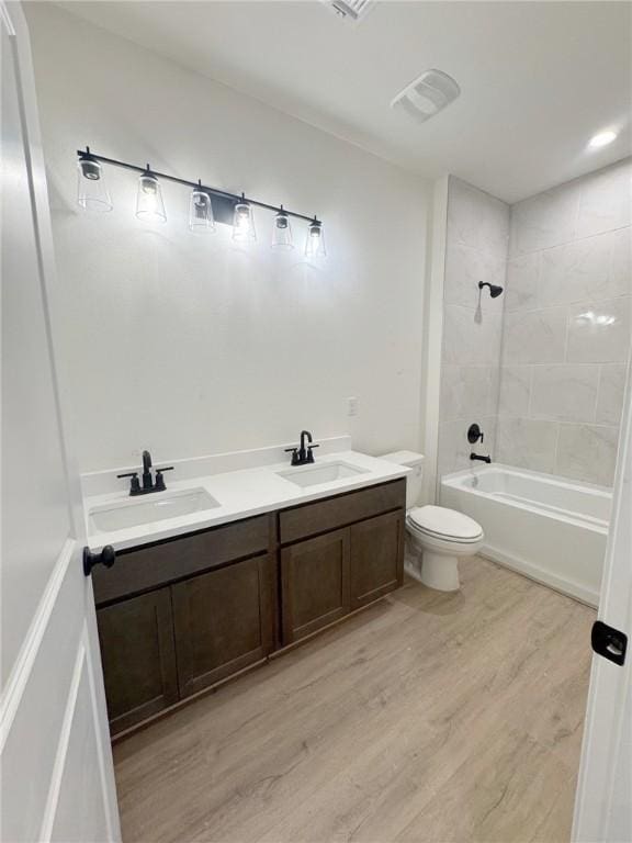 full bathroom featuring tiled shower / bath, wood-type flooring, toilet, and vanity