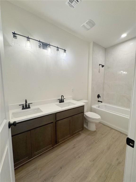 full bathroom featuring vanity, hardwood / wood-style floors, tiled shower / bath, and toilet