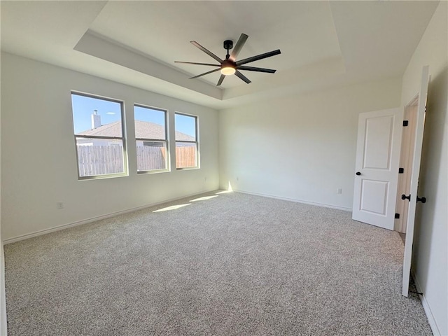 carpeted spare room featuring ceiling fan and a tray ceiling