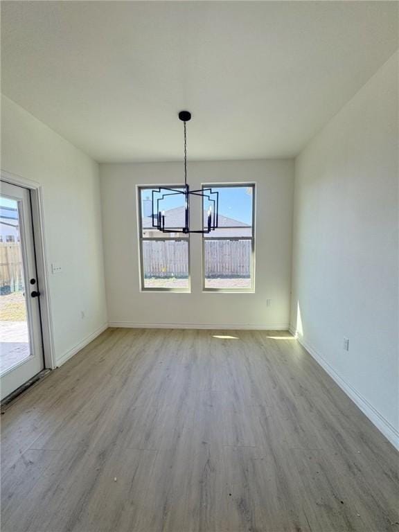 unfurnished dining area with an inviting chandelier and light hardwood / wood-style floors