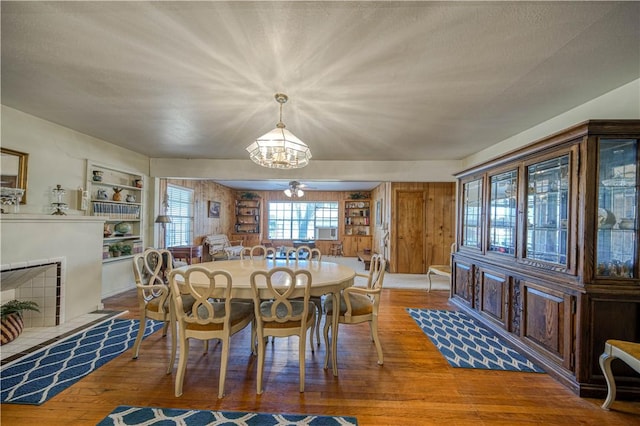 dining area featuring a notable chandelier, hardwood / wood-style flooring, a fireplace, and built in shelves