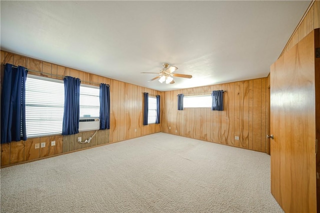 carpeted empty room with wooden walls, cooling unit, and ceiling fan