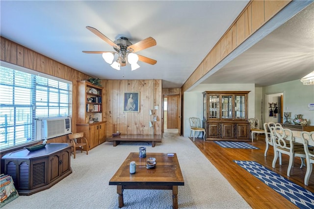 living room with cooling unit, hardwood / wood-style flooring, ceiling fan, and wood walls