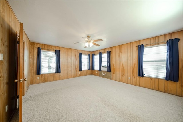 carpeted spare room featuring ceiling fan and wood walls