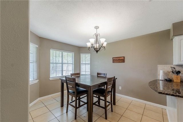 5929 Choctaw Dr, Corpus Christi, TX 78415 - dining area with a chandelier, light tile patterned flooring, baseboards, and a textured ceiling