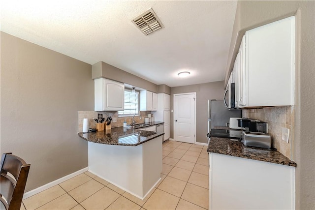 5929 Choctaw Dr, Corpus Christi, TX 78415 - kitchen with stainless steel microwave, a sink, decorative backsplash, and white cabinets