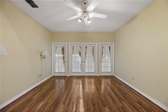 unfurnished room with ceiling fan, dark wood-type flooring, a textured ceiling, and french doors