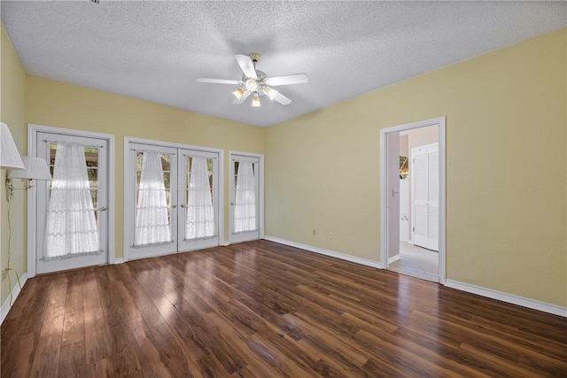 empty room featuring french doors, ceiling fan, dark hardwood / wood-style flooring, and a textured ceiling