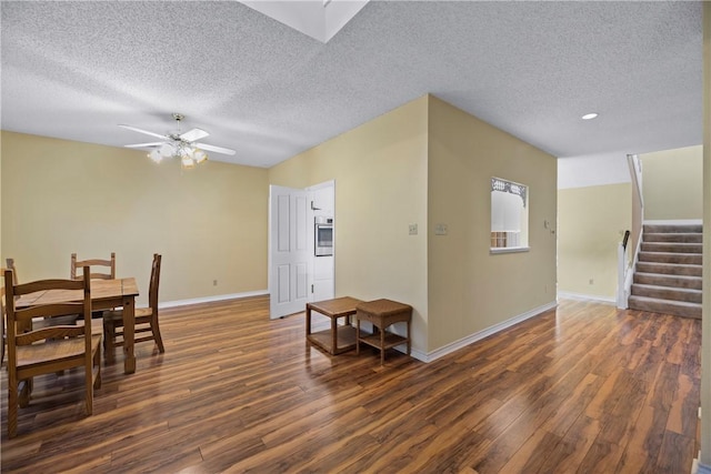 dining space featuring ceiling fan, dark wood-type flooring, and a textured ceiling