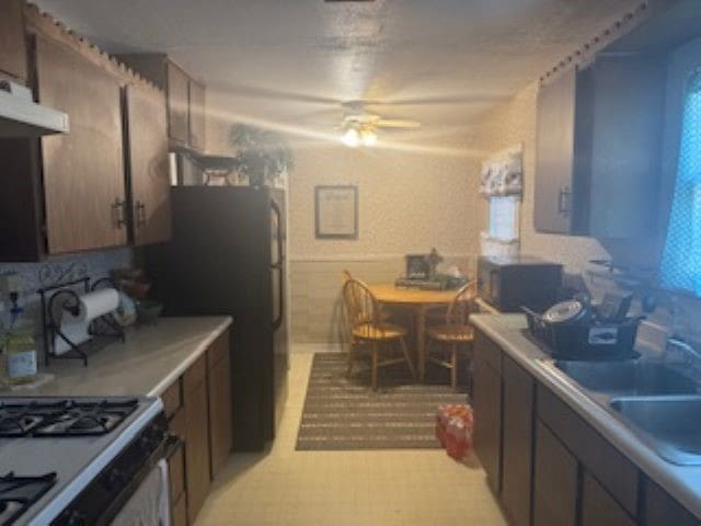 kitchen with black appliances, ceiling fan, dark brown cabinets, and sink
