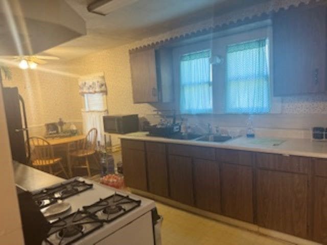 kitchen with stainless steel fridge, gas range gas stove, sink, and ceiling fan