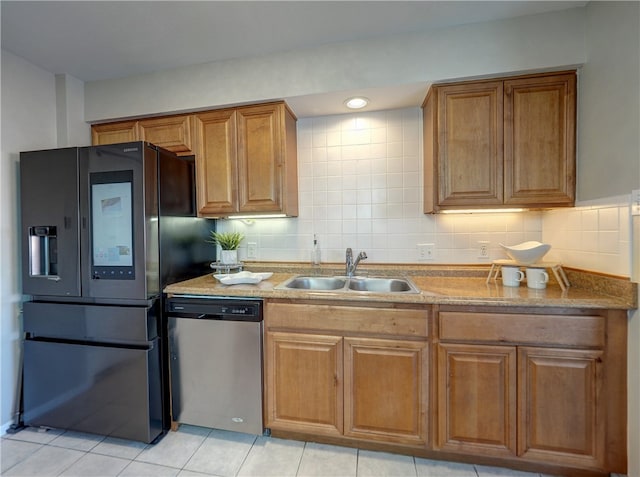 kitchen with black fridge with ice dispenser, light tile patterned floors, decorative backsplash, sink, and stainless steel dishwasher