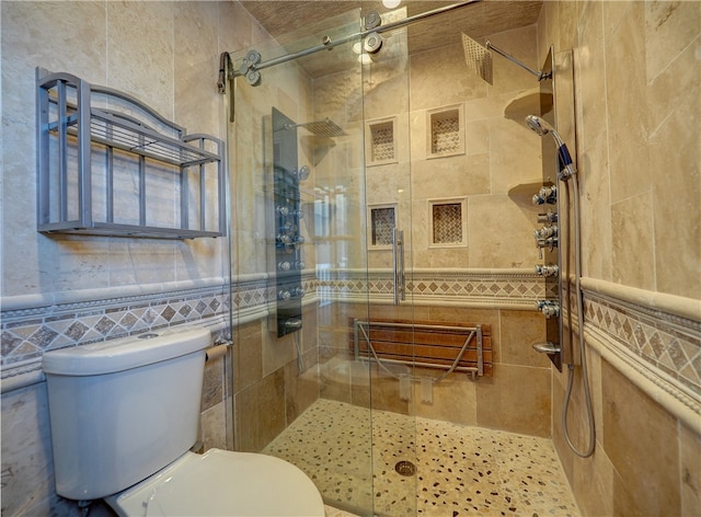 bathroom featuring a shower with door, toilet, and tile walls