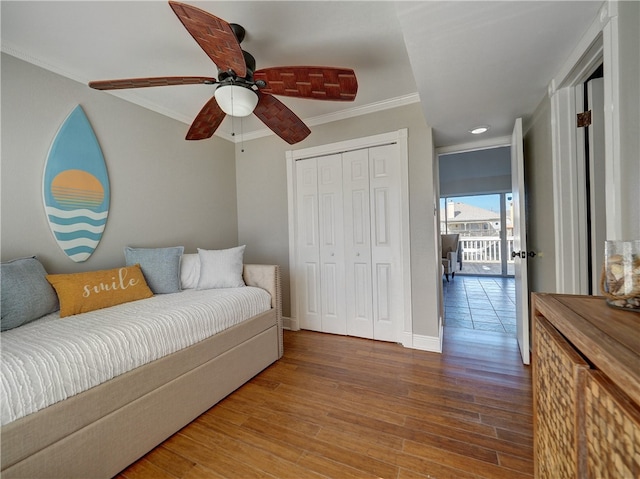 bedroom featuring ceiling fan, wood-type flooring, a closet, and ornamental molding