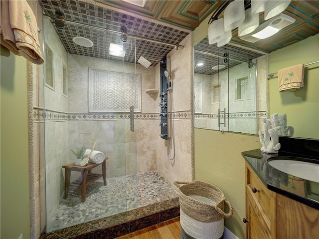 bathroom with hardwood / wood-style floors, vanity, and a tile shower