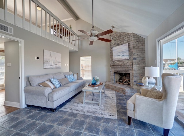 living room featuring a brick fireplace, dark wood-type flooring, high vaulted ceiling, beamed ceiling, and ceiling fan