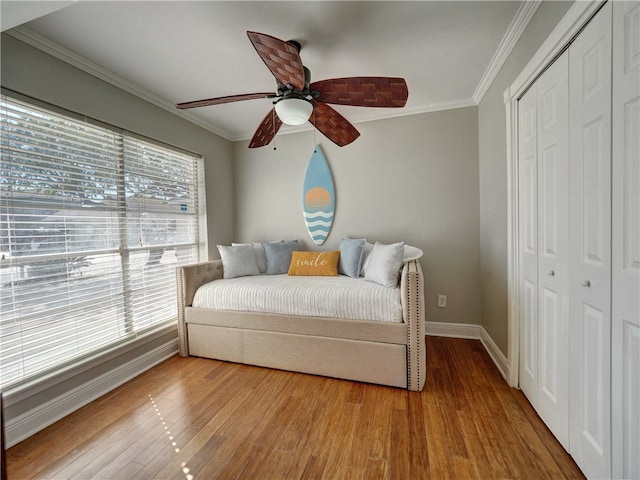 bedroom featuring ornamental molding, a closet, hardwood / wood-style flooring, and ceiling fan