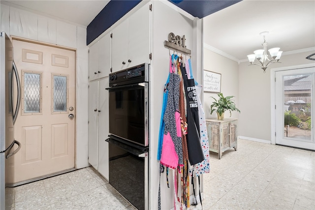 kitchen with white cabinets, a notable chandelier, ornamental molding, black double oven, and stainless steel refrigerator