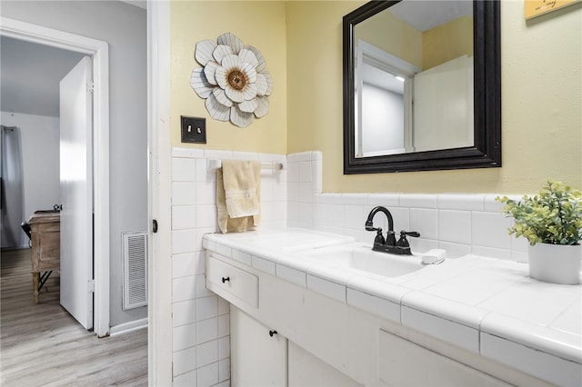 bathroom with hardwood / wood-style floors, vanity, and tile walls