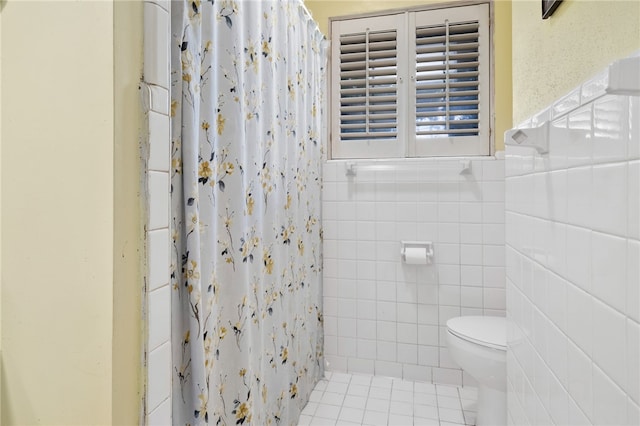 bathroom with a shower with curtain, tile patterned floors, toilet, and tile walls