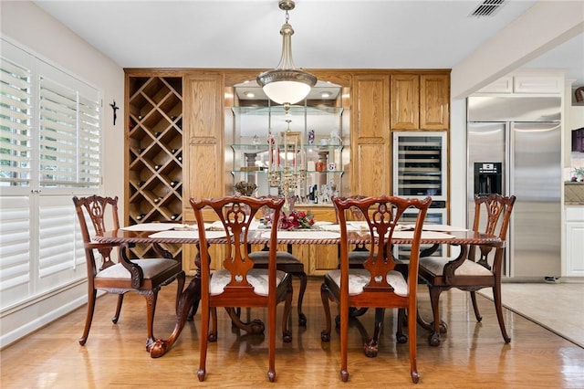 dining space with visible vents, light wood-style flooring, and wine cooler