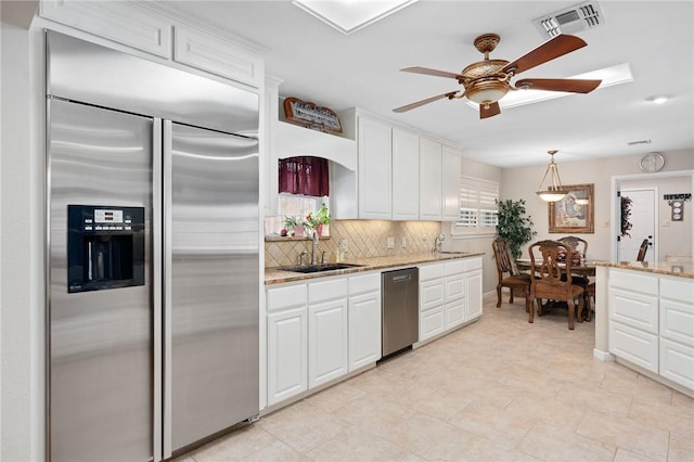 kitchen with stainless steel appliances, backsplash, a sink, visible vents, and a ceiling fan
