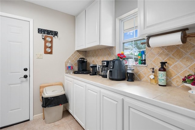 kitchen featuring tile counters, light tile patterned flooring, backsplash, baseboards, and white cabinets
