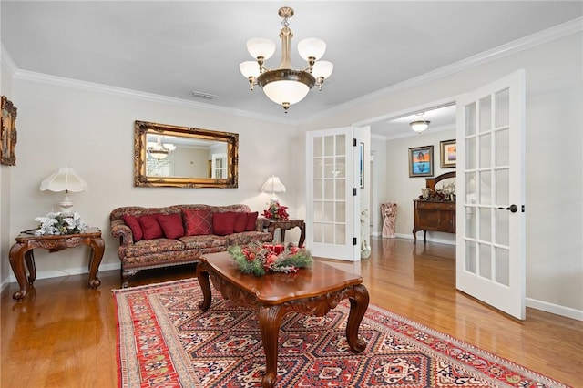 living area featuring ornamental molding, visible vents, wood finished floors, and french doors
